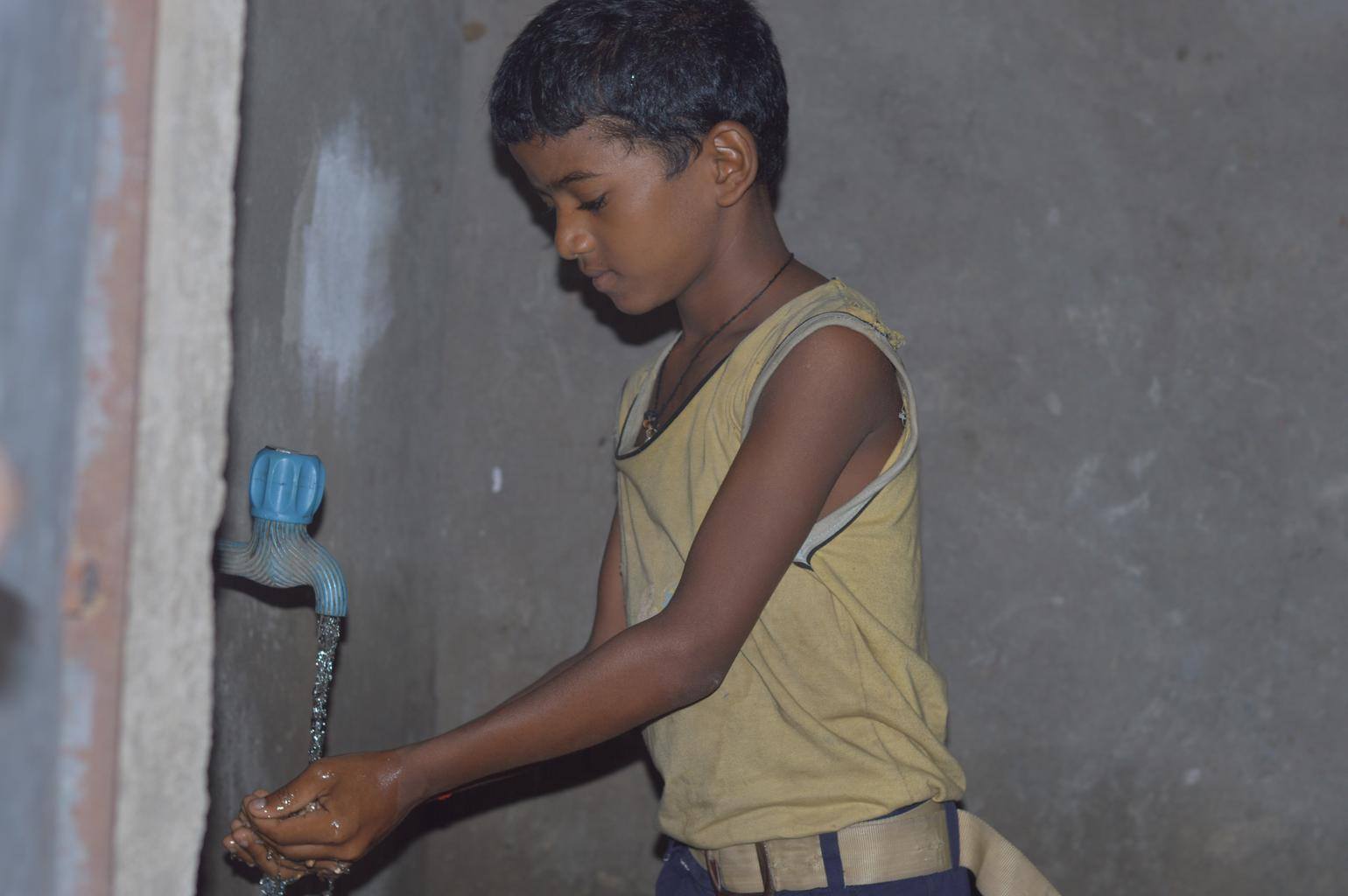 young boy getting water from the new well
